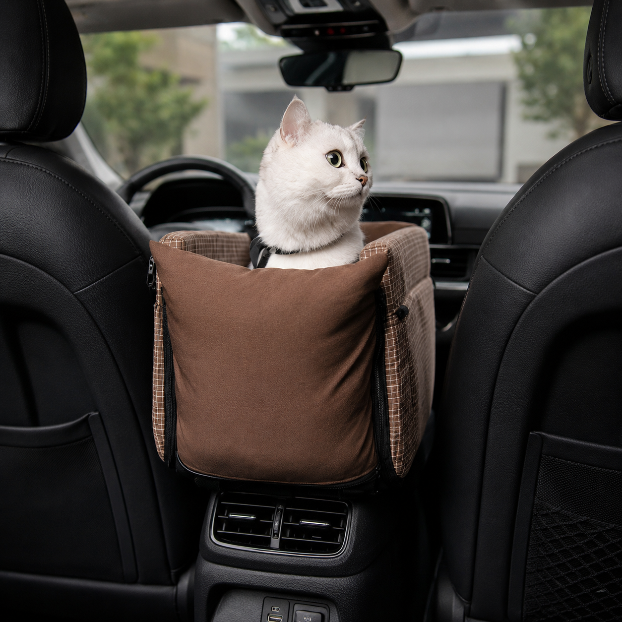 Cat sitting in a center console pet car seat between the front seats