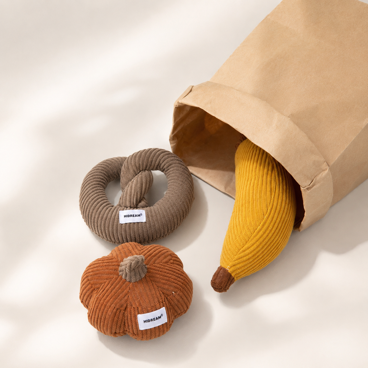 Three soft cat toys coming out of a paper storage bag