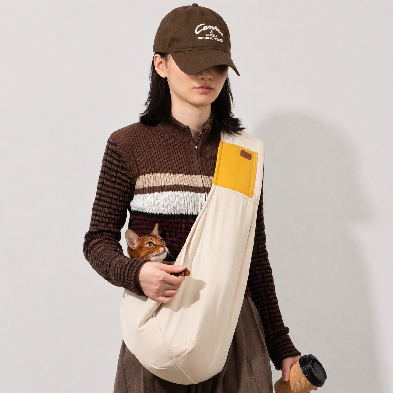 Woman carrying a cat in a soft cotton sling carrier