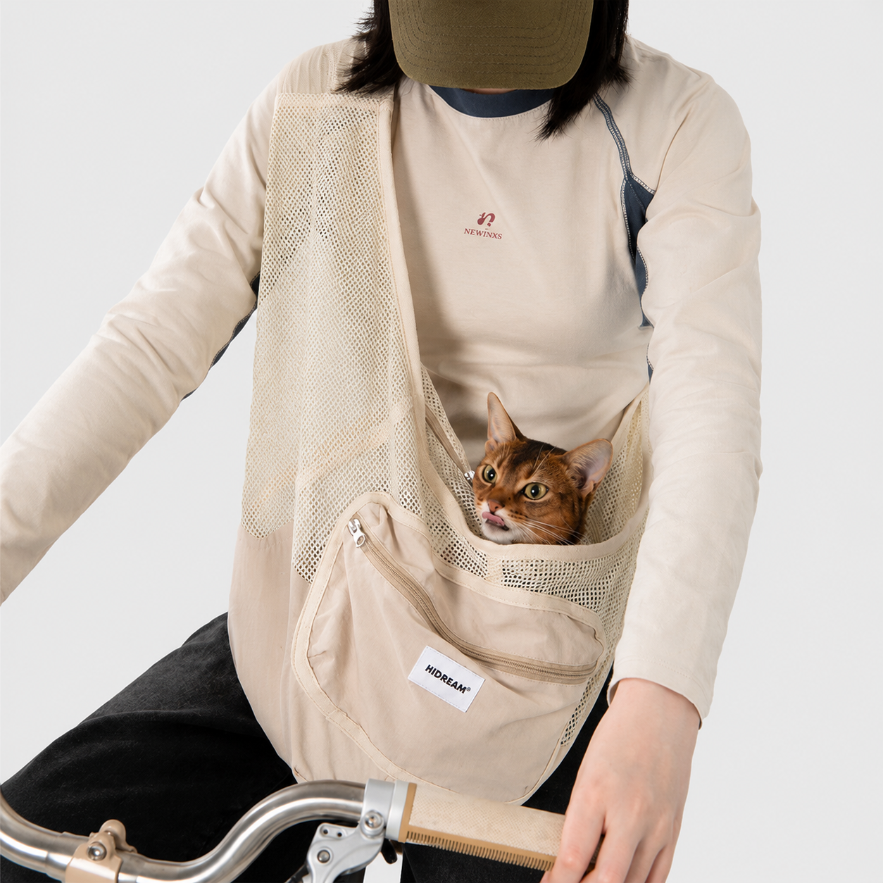 Cat sitting inside a beige breathable pet sling carrier